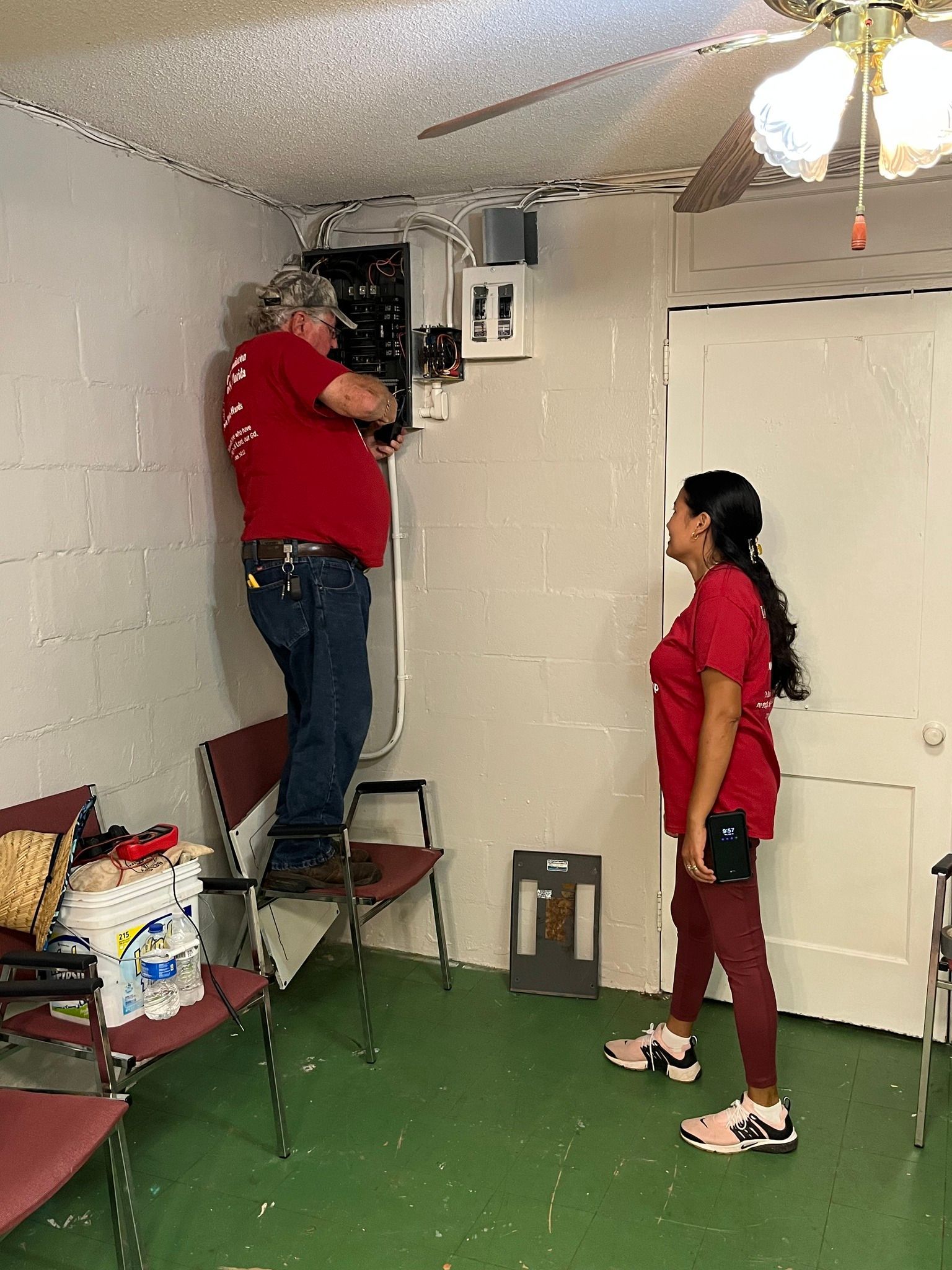 A man and a woman are working on a wall in a room.