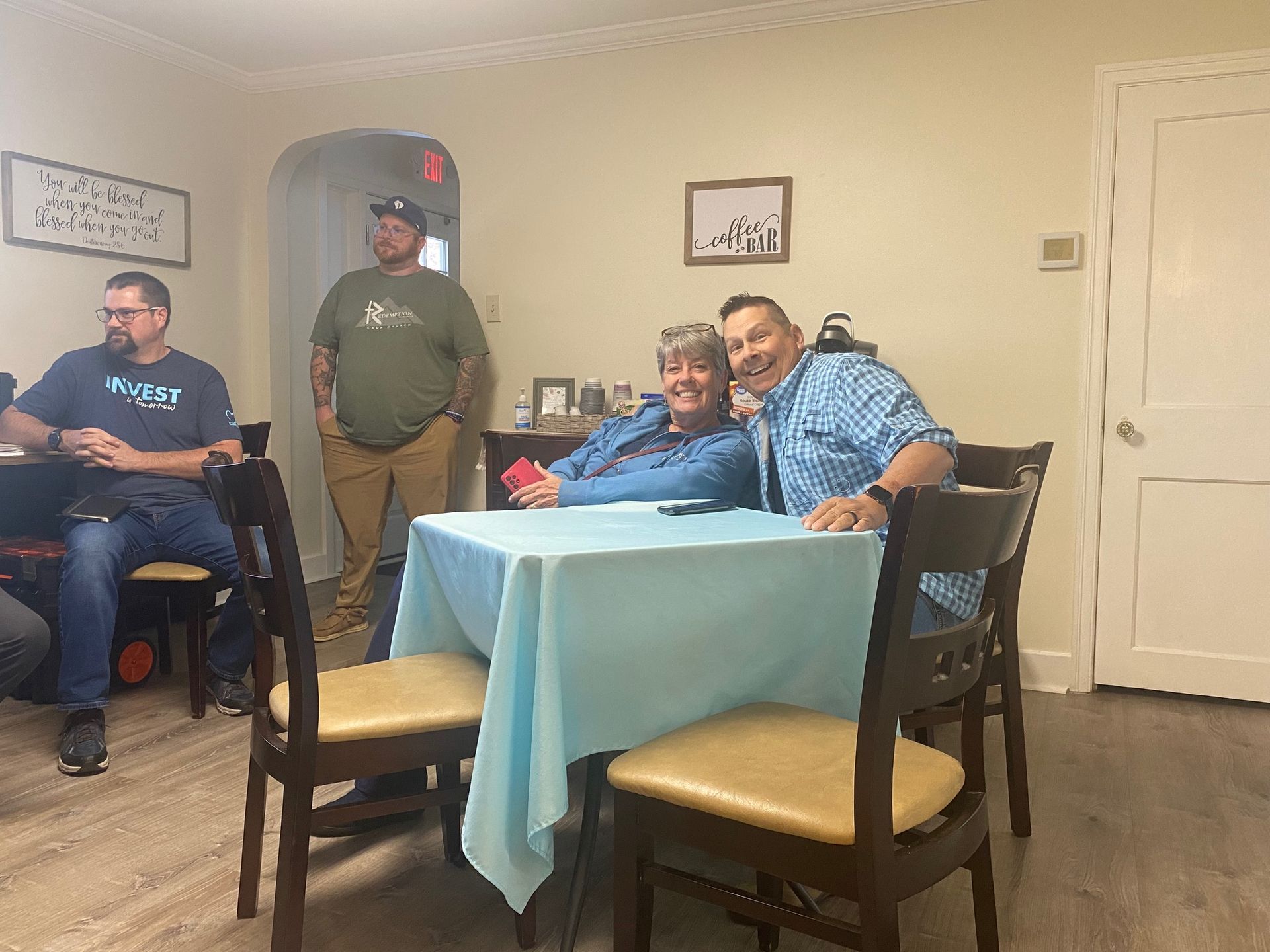 A group of people are sitting at a table in a living room.