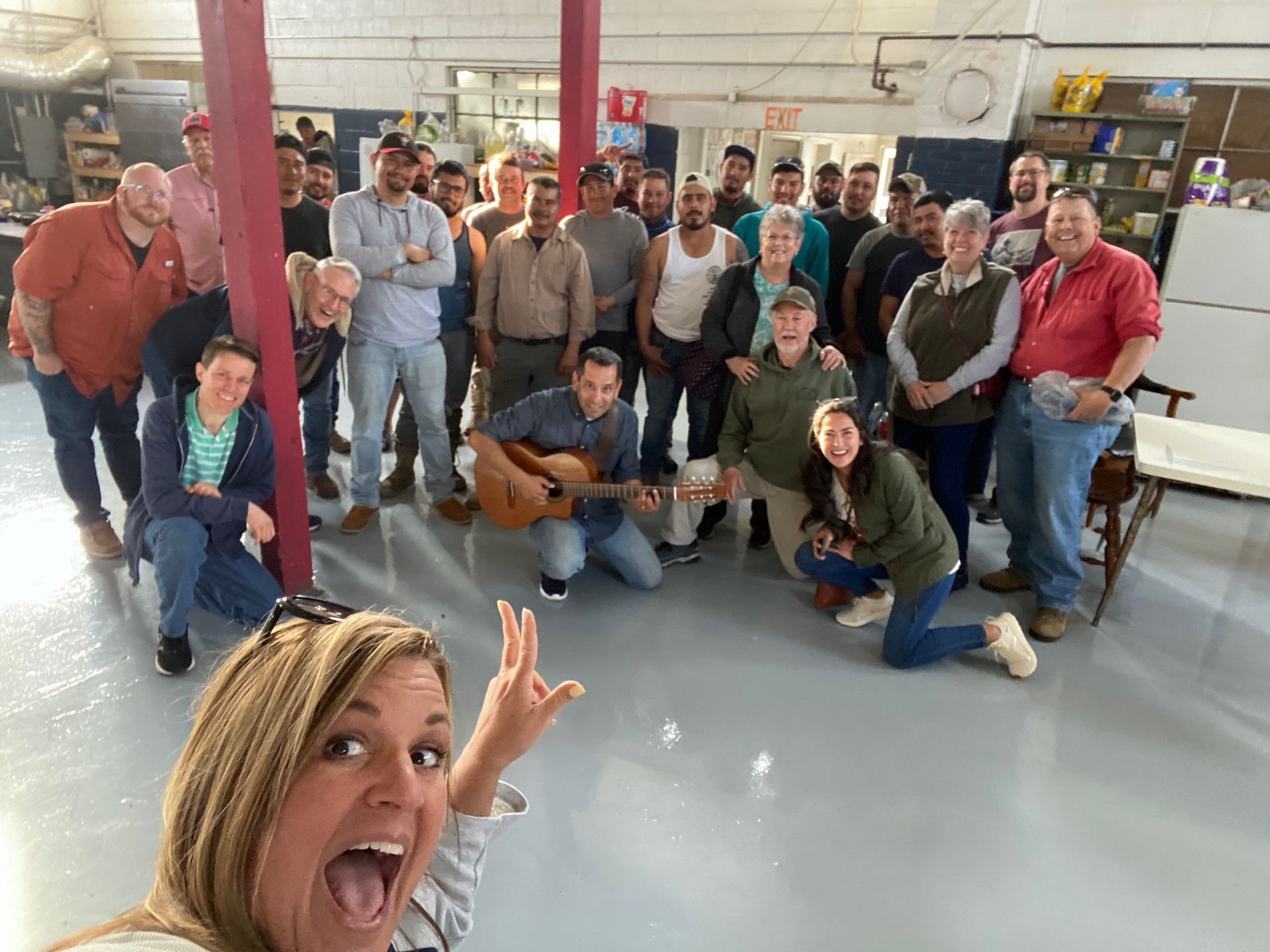 A group of people are posing for a picture in a room with a man playing a guitar.