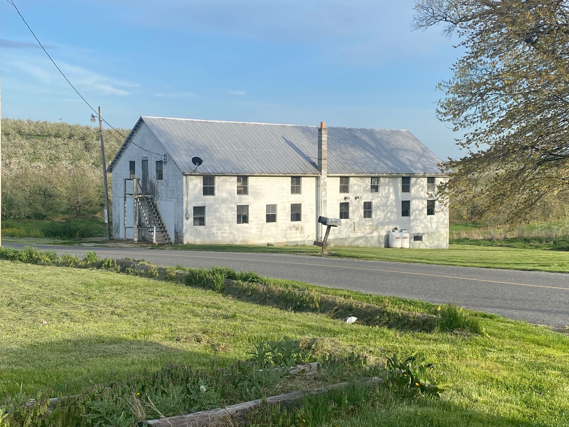 A large white building is sitting in the middle of a grassy field.