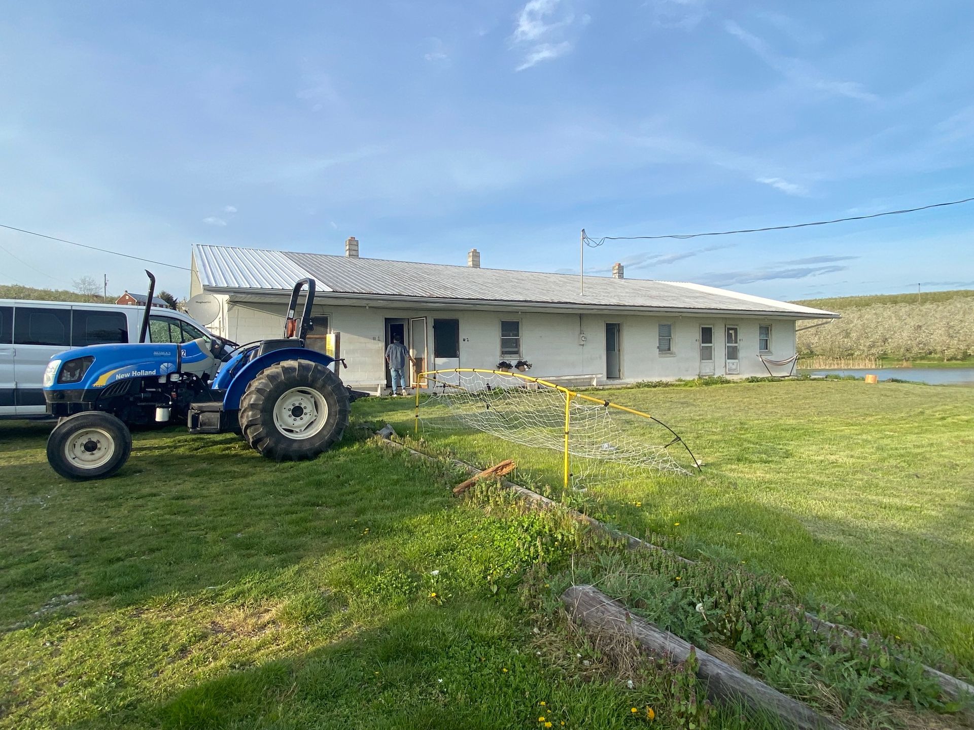 A blue tractor is parked in front of a white house.