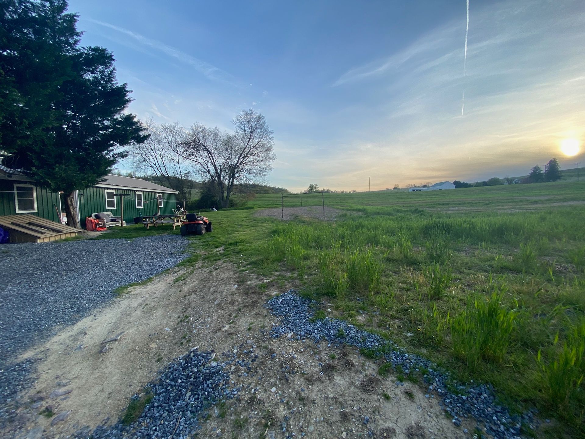 A green house is sitting in the middle of a grassy field.