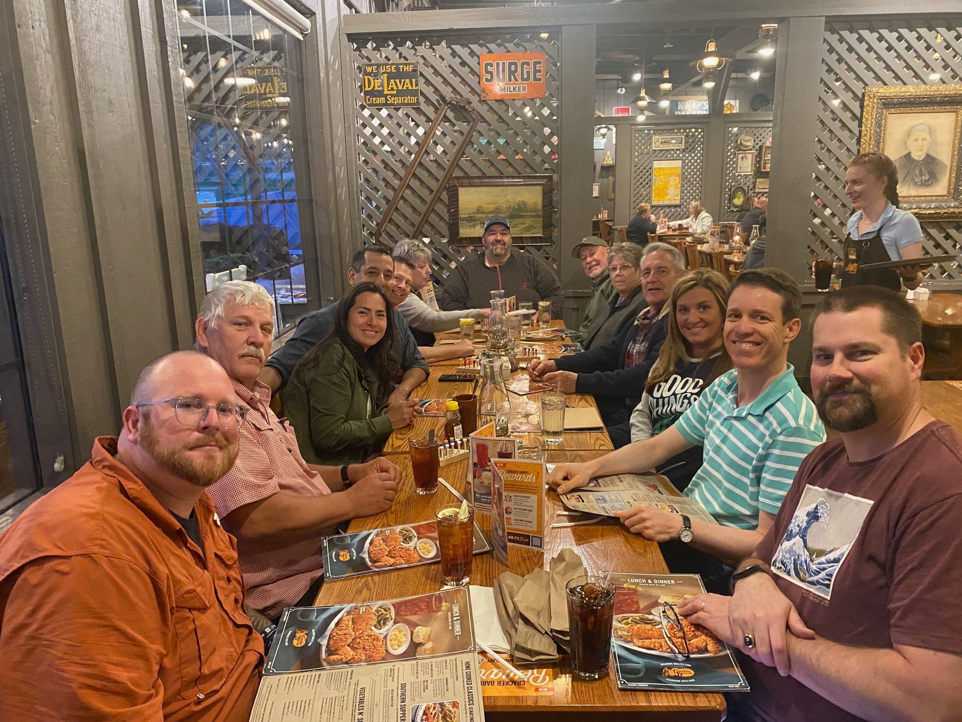 A group of people are sitting at a long table in a restaurant.