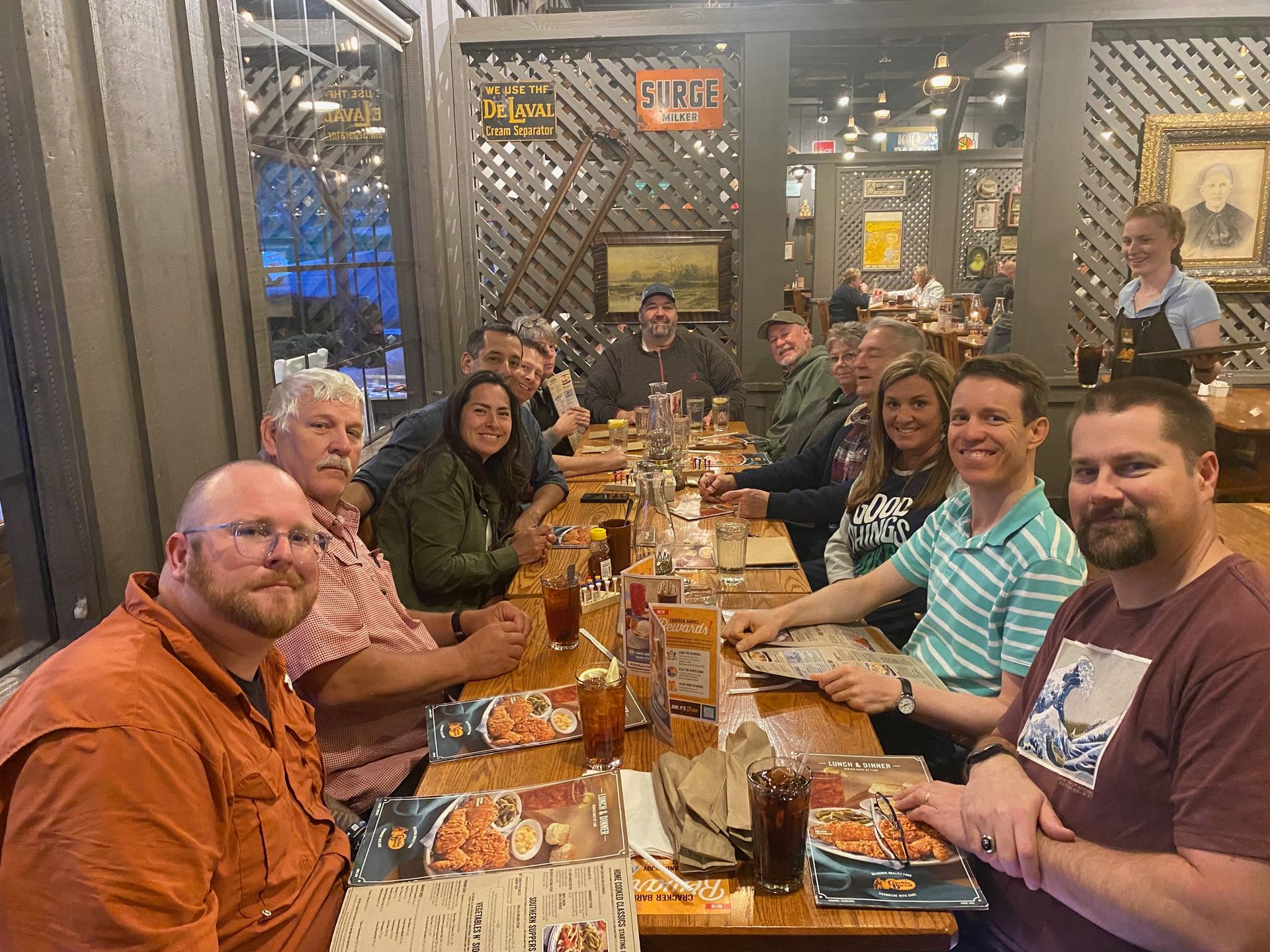 A group of people are sitting at a long table in a restaurant.