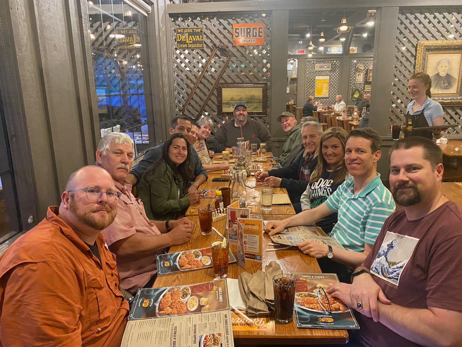 A group of people are sitting at a long table in a restaurant.