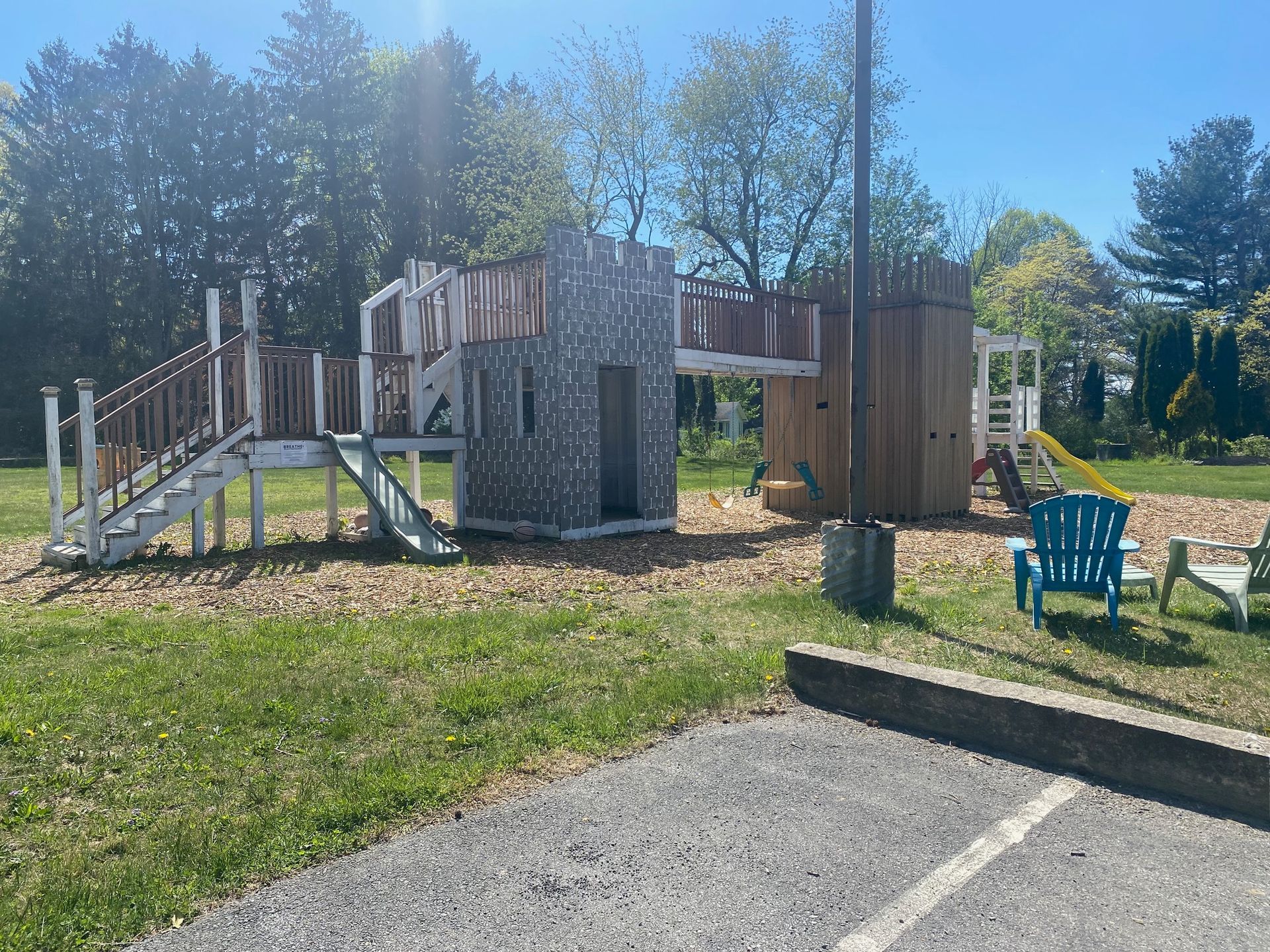 A playground with a house and stairs in the middle of a park.