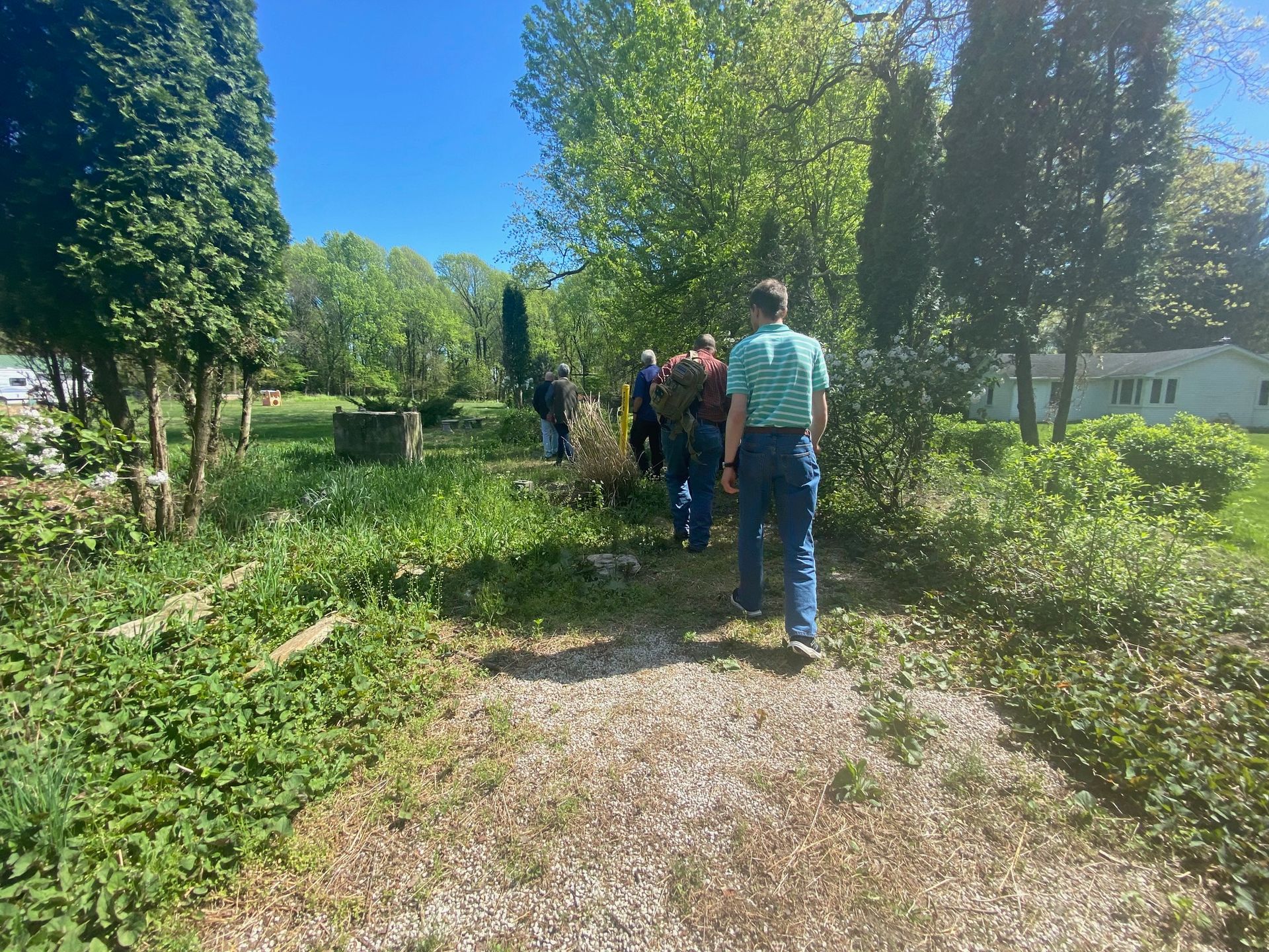 A group of people are walking down a dirt path in a park.