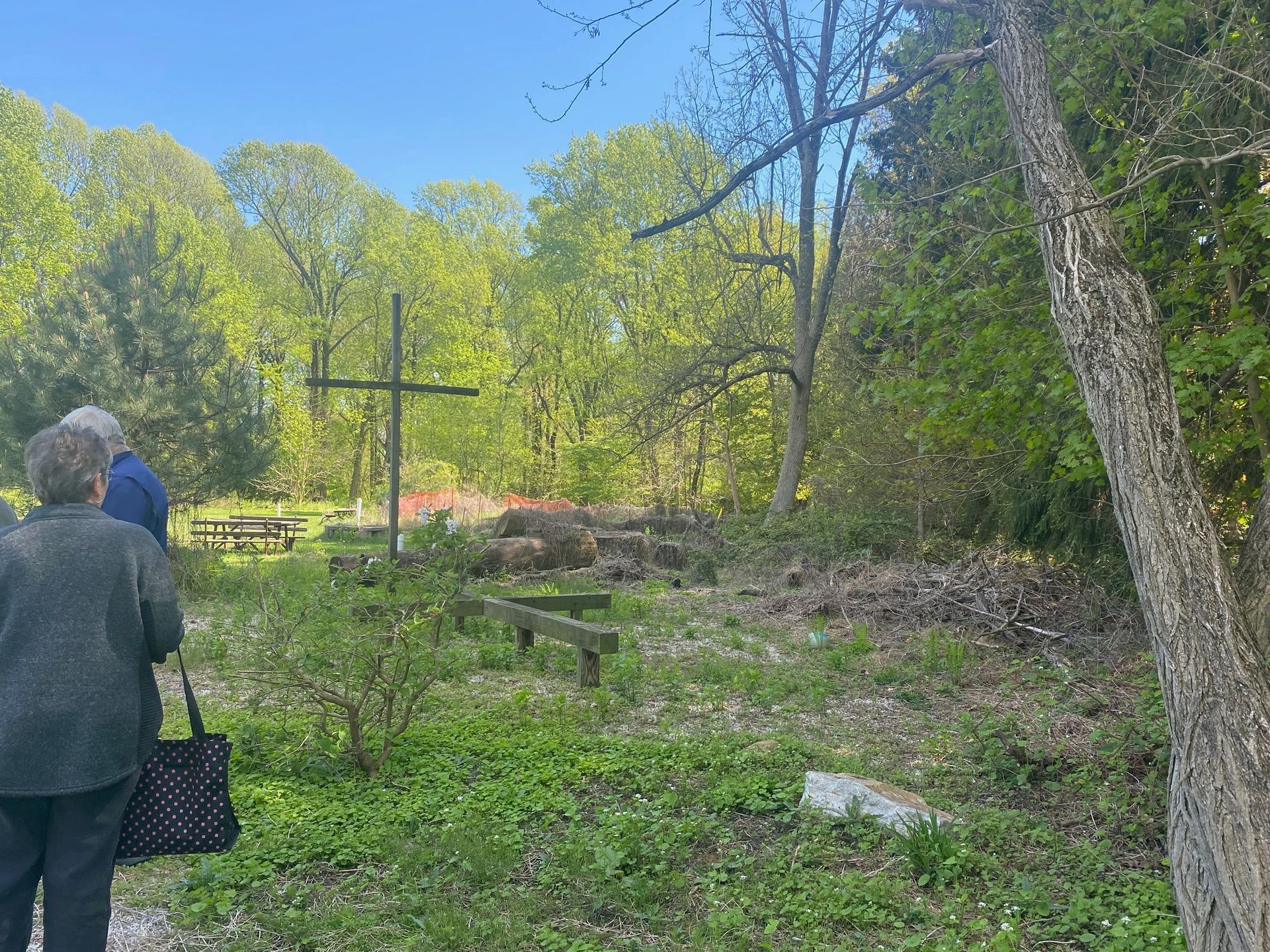 A couple of people standing in a field with a cross in the background.