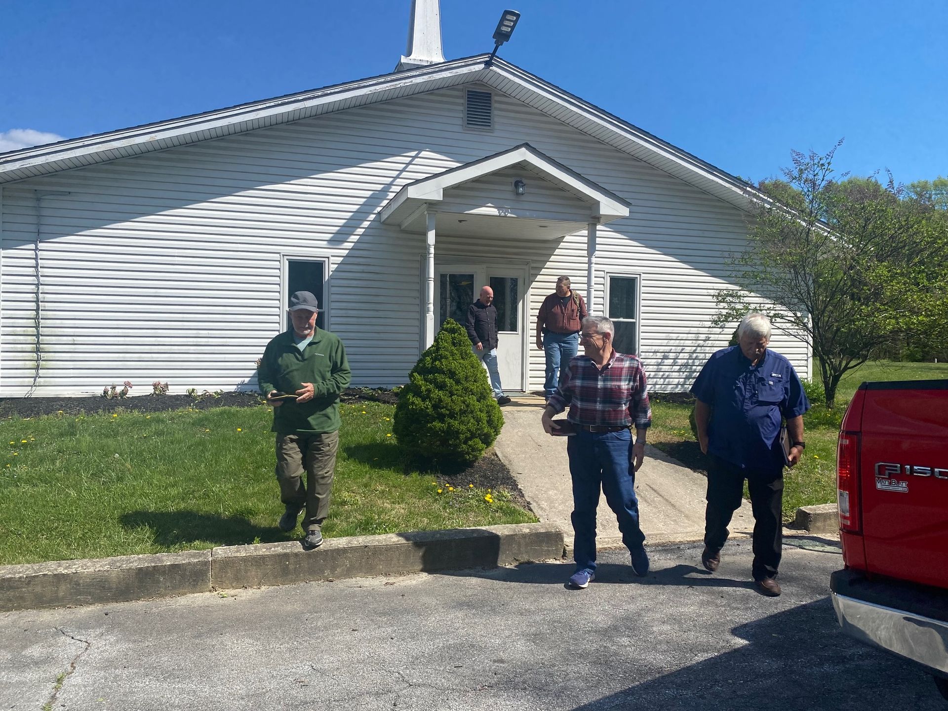 A group of people are walking in front of a white building.