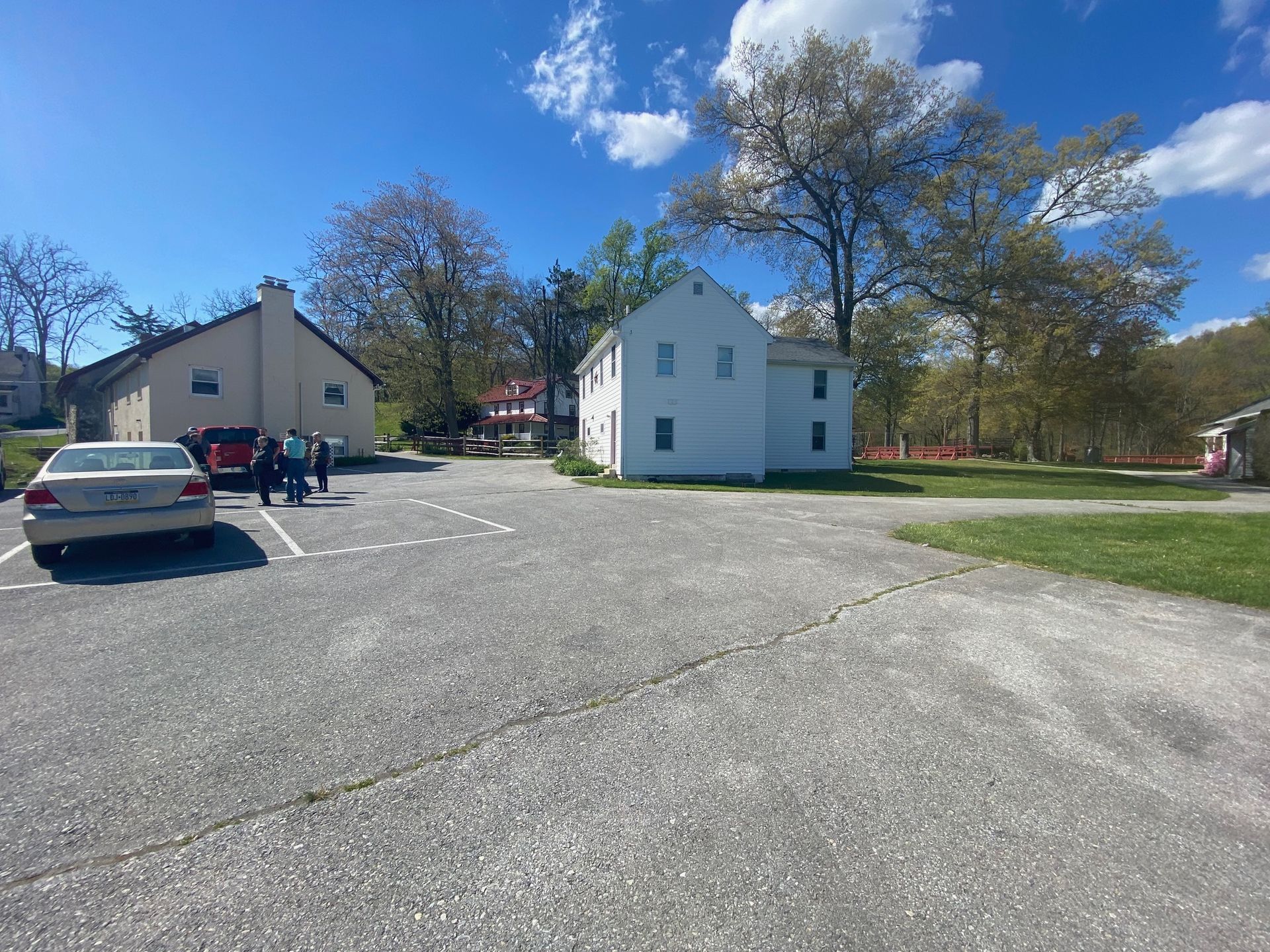 A white car is parked in a parking lot in front of a white house