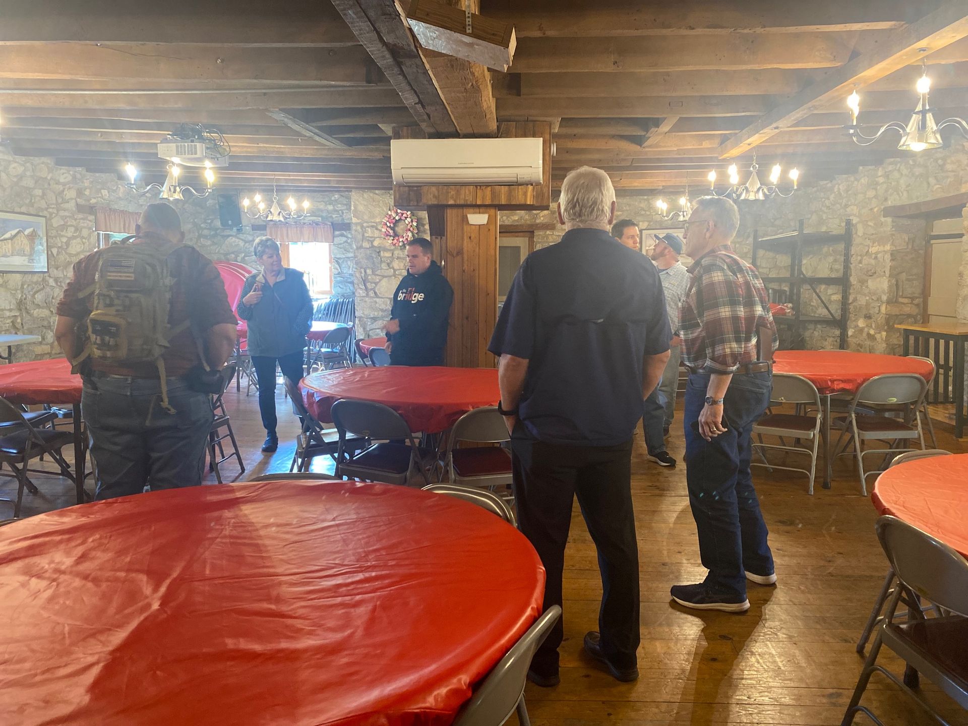 A group of people are standing around tables in a room.