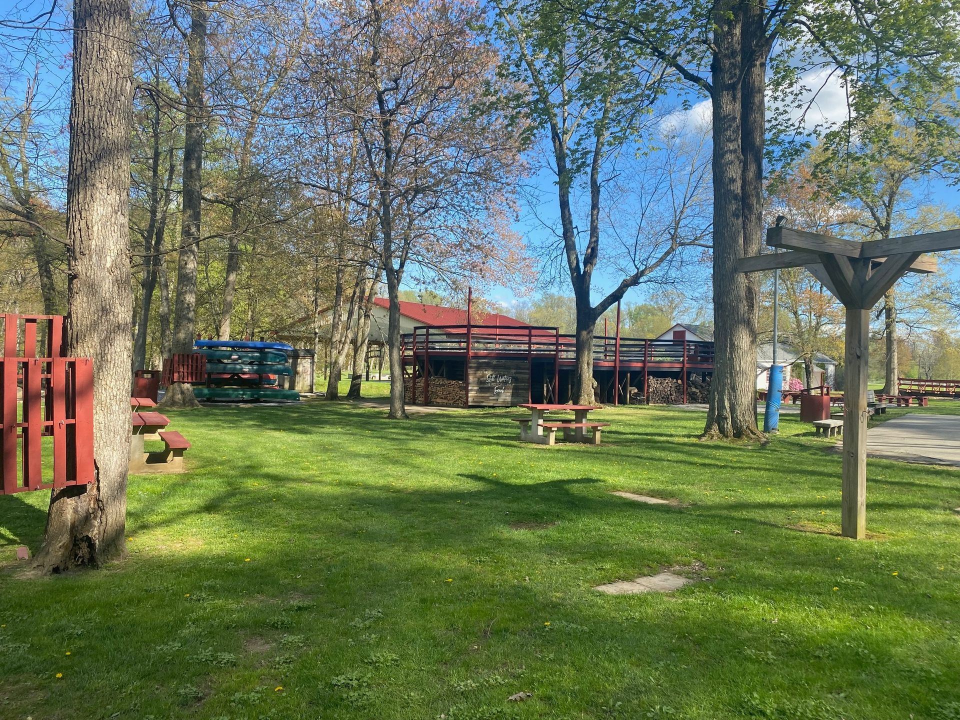 A picnic area in a park with a red fence and trees.