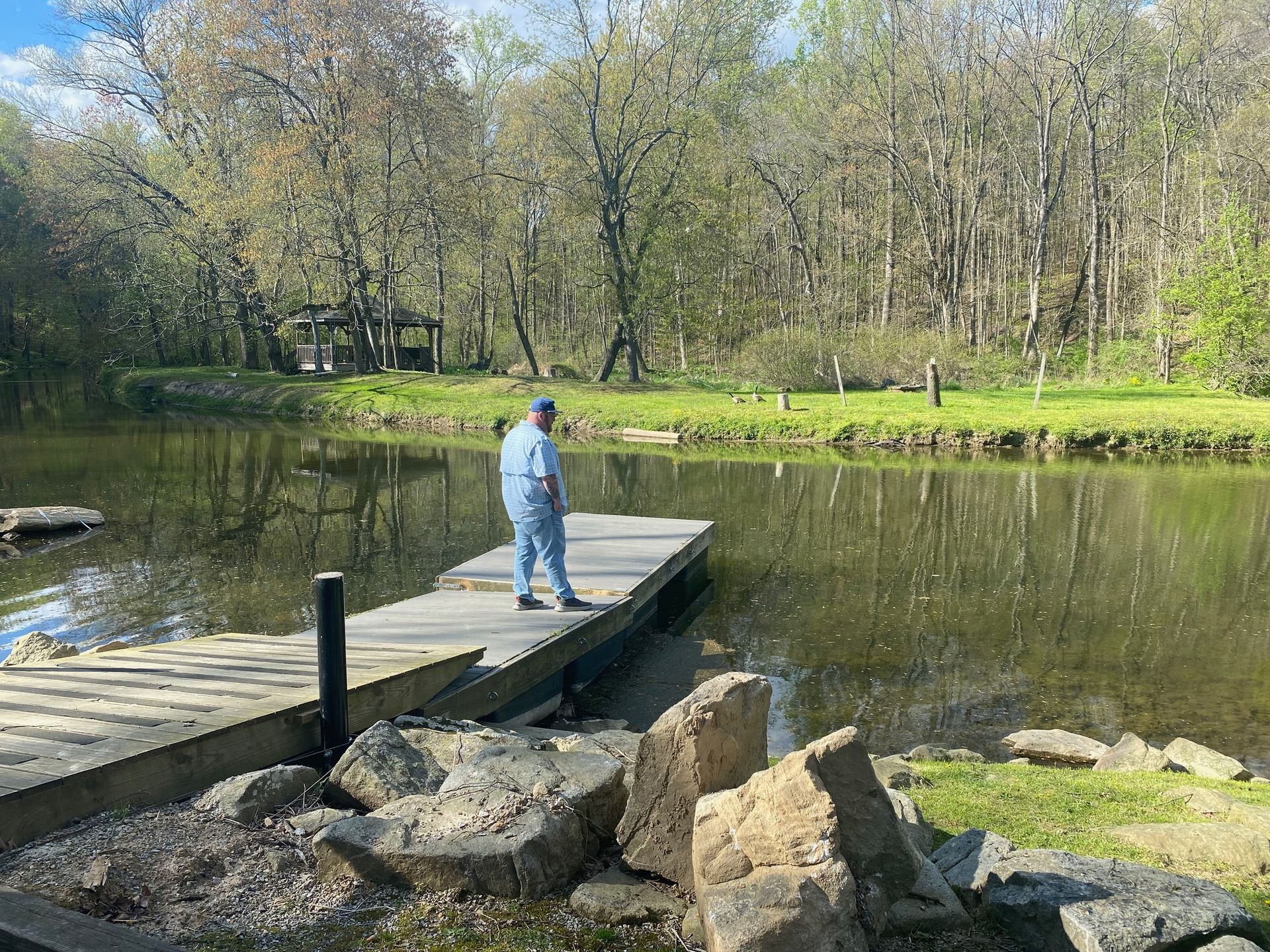 A man is standing on a dock overlooking a lake.