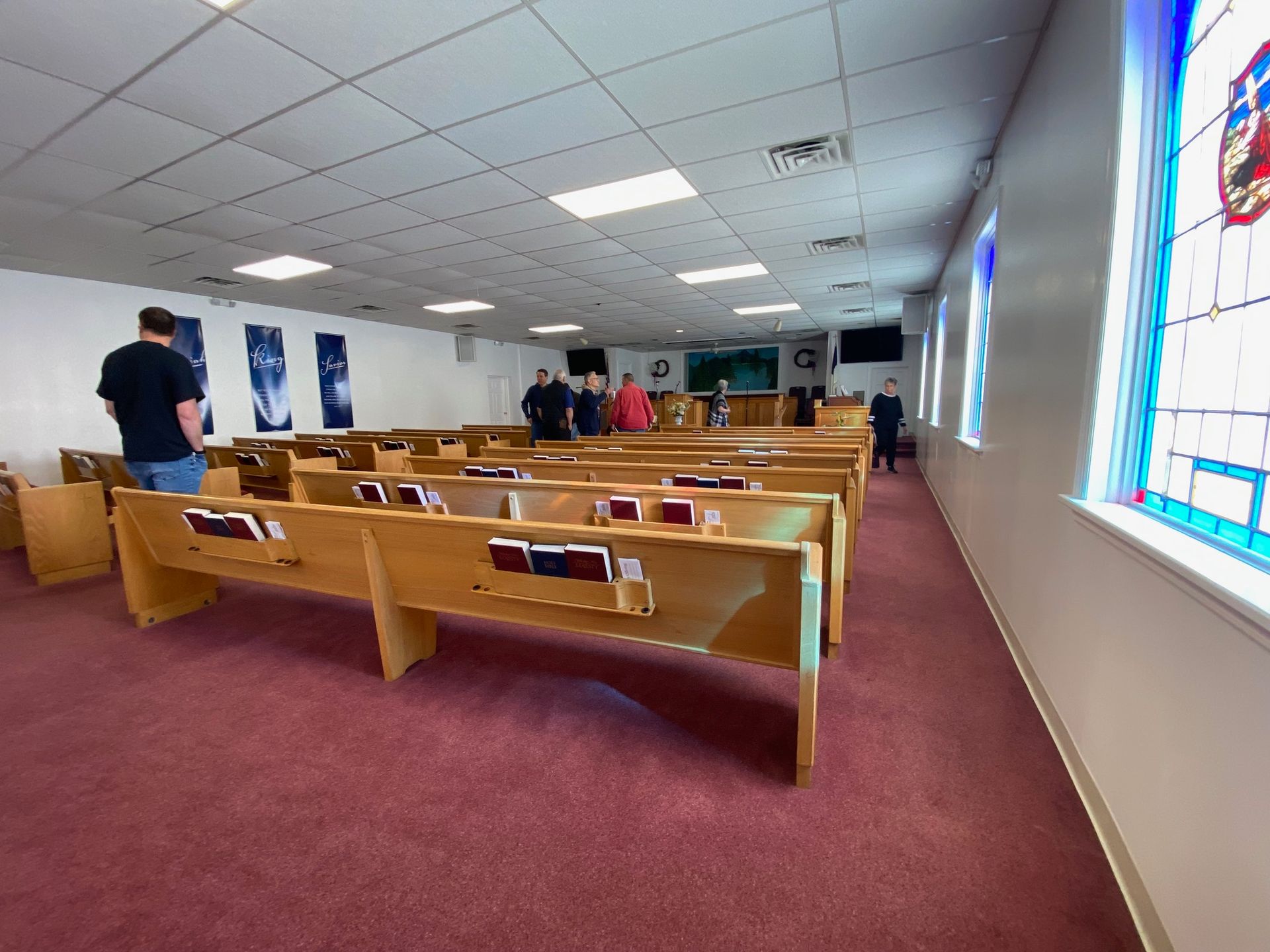 A church with rows of wooden benches and stained glass windows