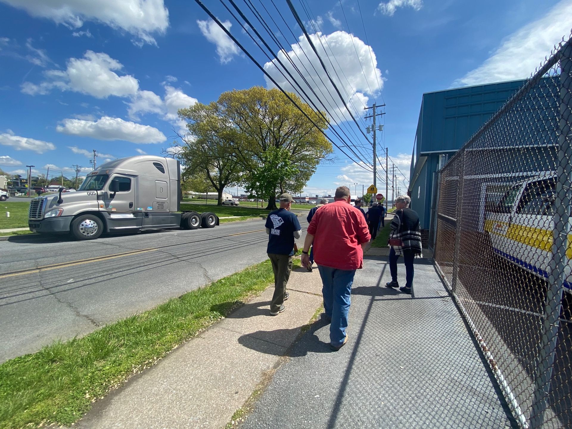 A group of people are walking down a sidewalk next to a truck.