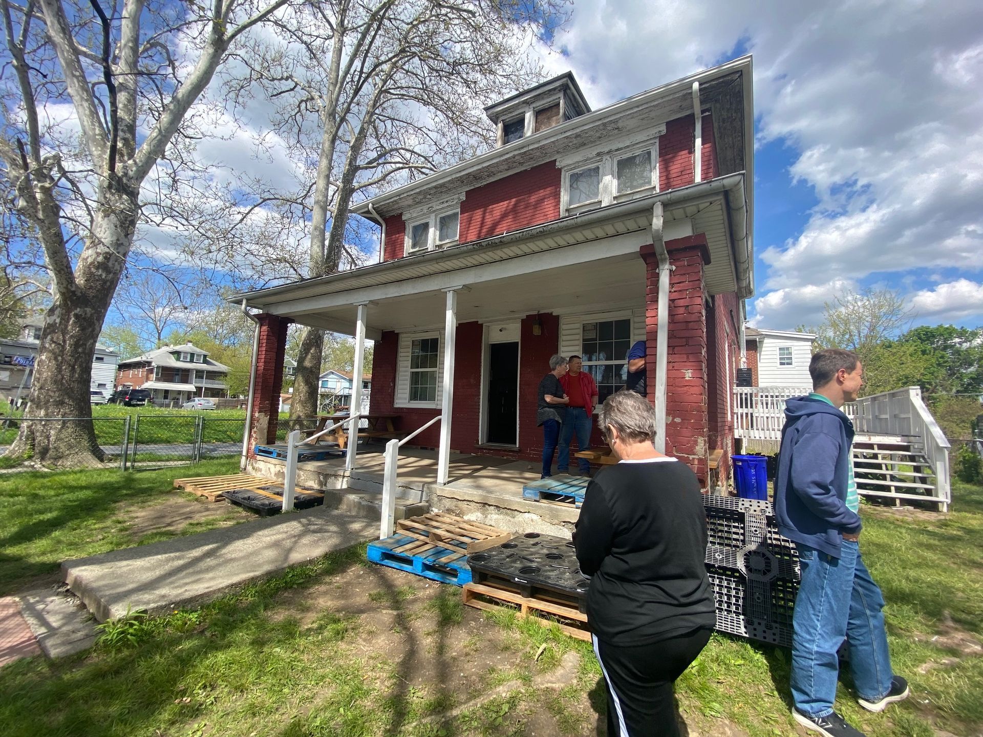 A group of people are standing in front of a red house.