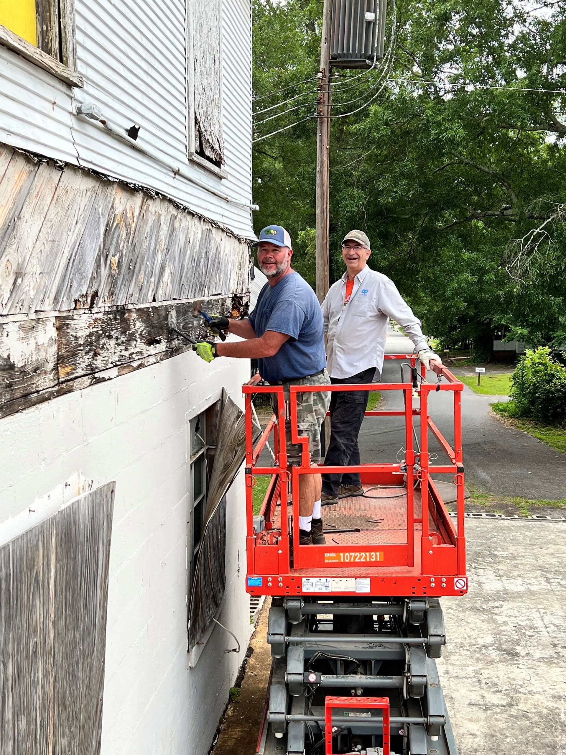 Two men are working on the side of a building on a scissor lift.