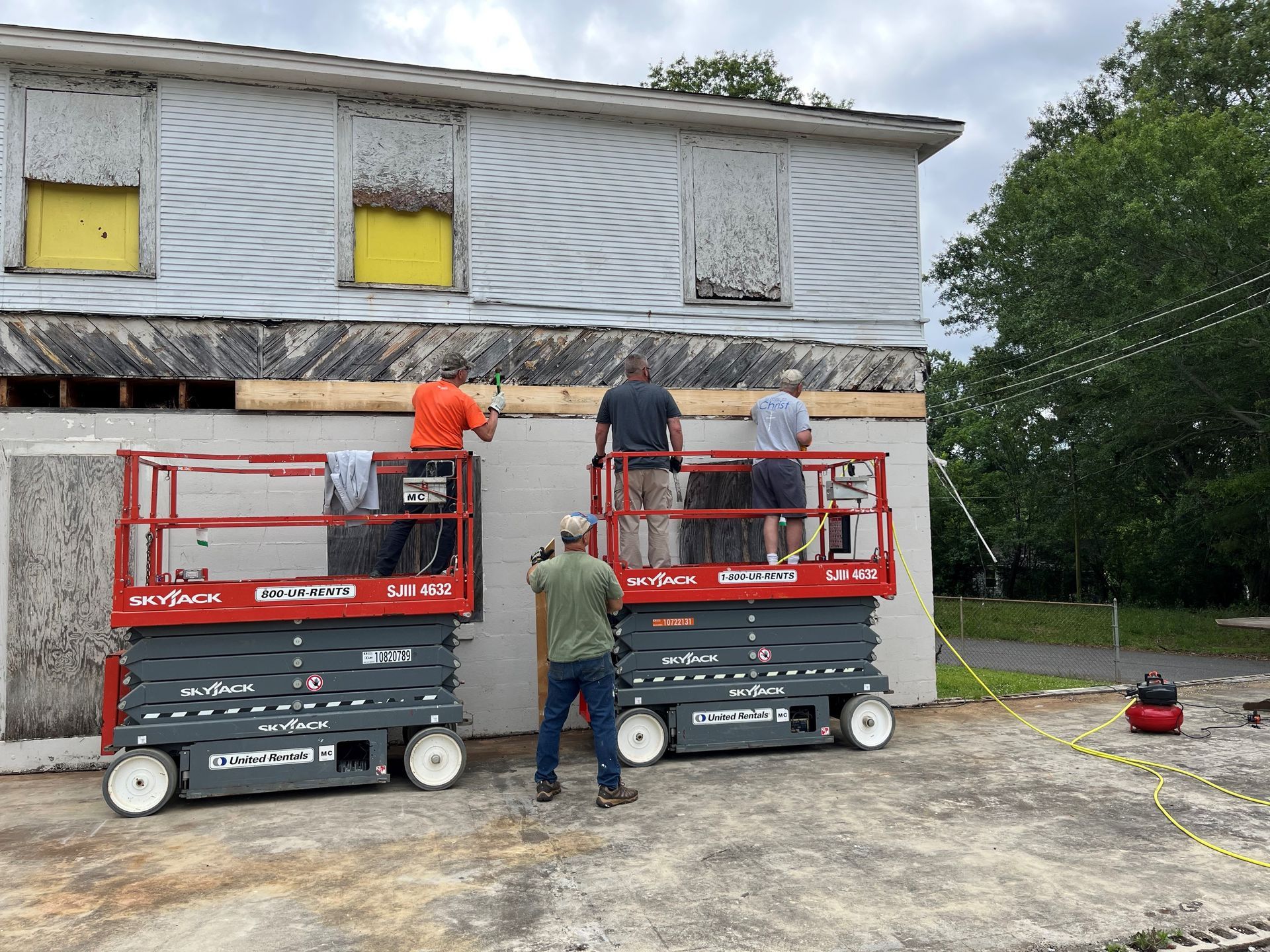 A group of men are working on a building with scissor lifts.