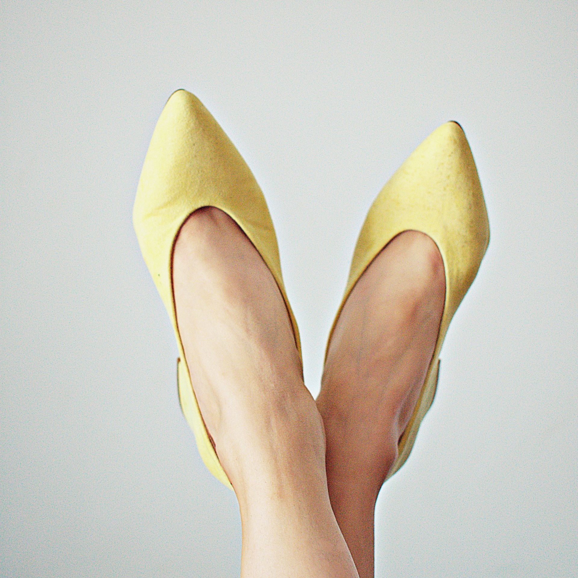 A pair of yellow shoes on a woman 's feet