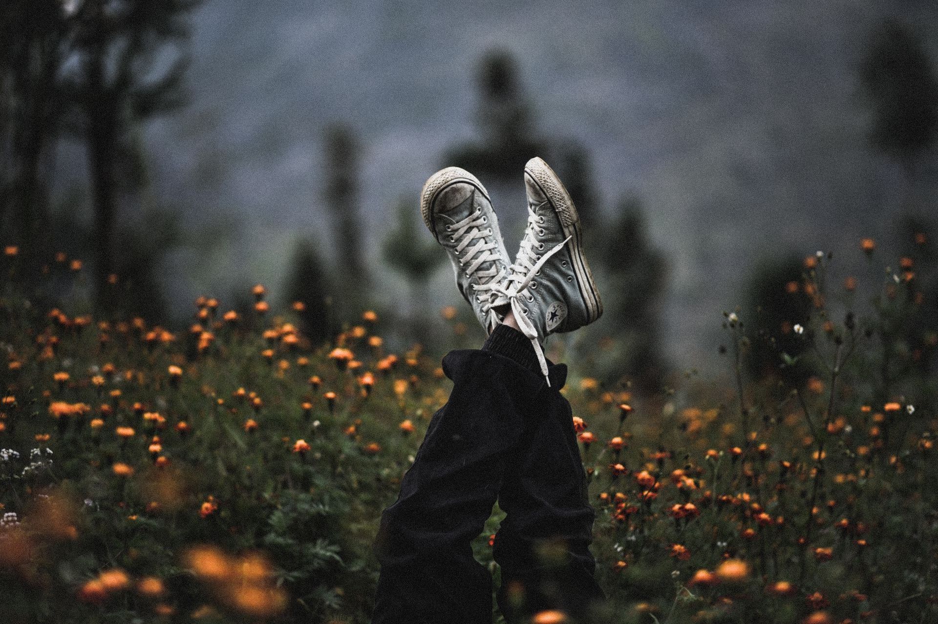 A person 's feet are sticking out of a field of flowers.