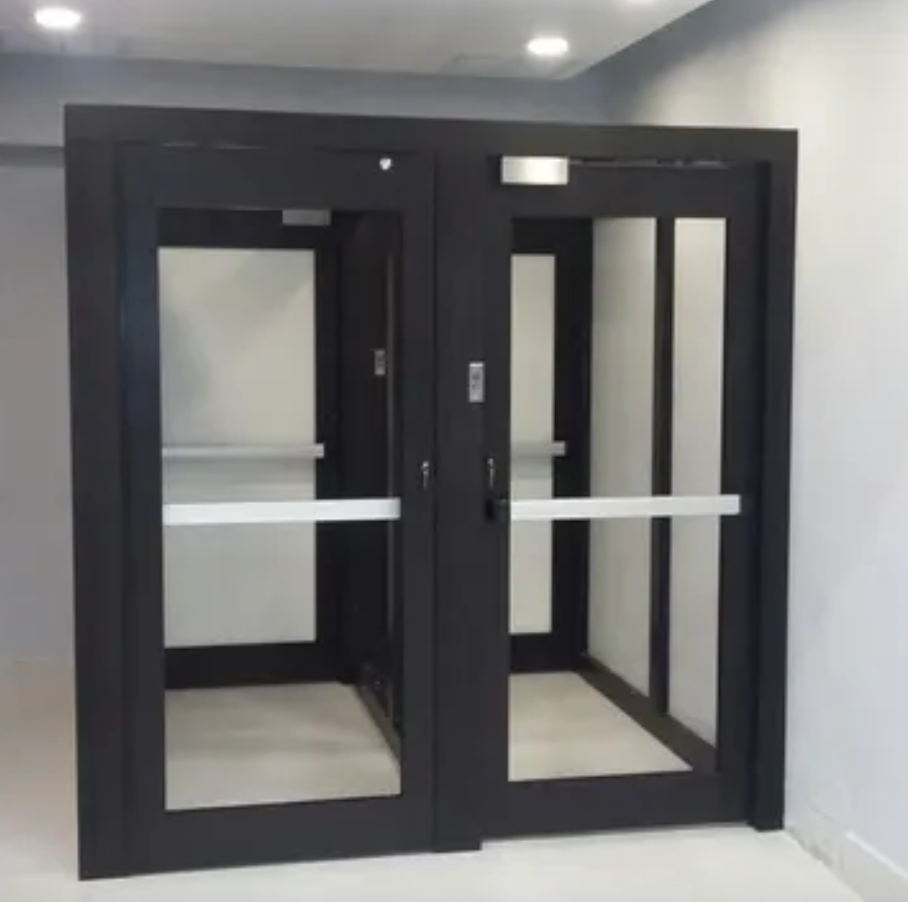 Two black-framed glass sliding doors in a gray hallway