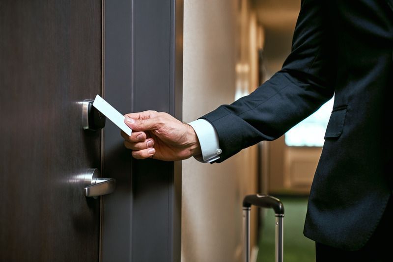 Person in a dark suit using a door key card to open a room door