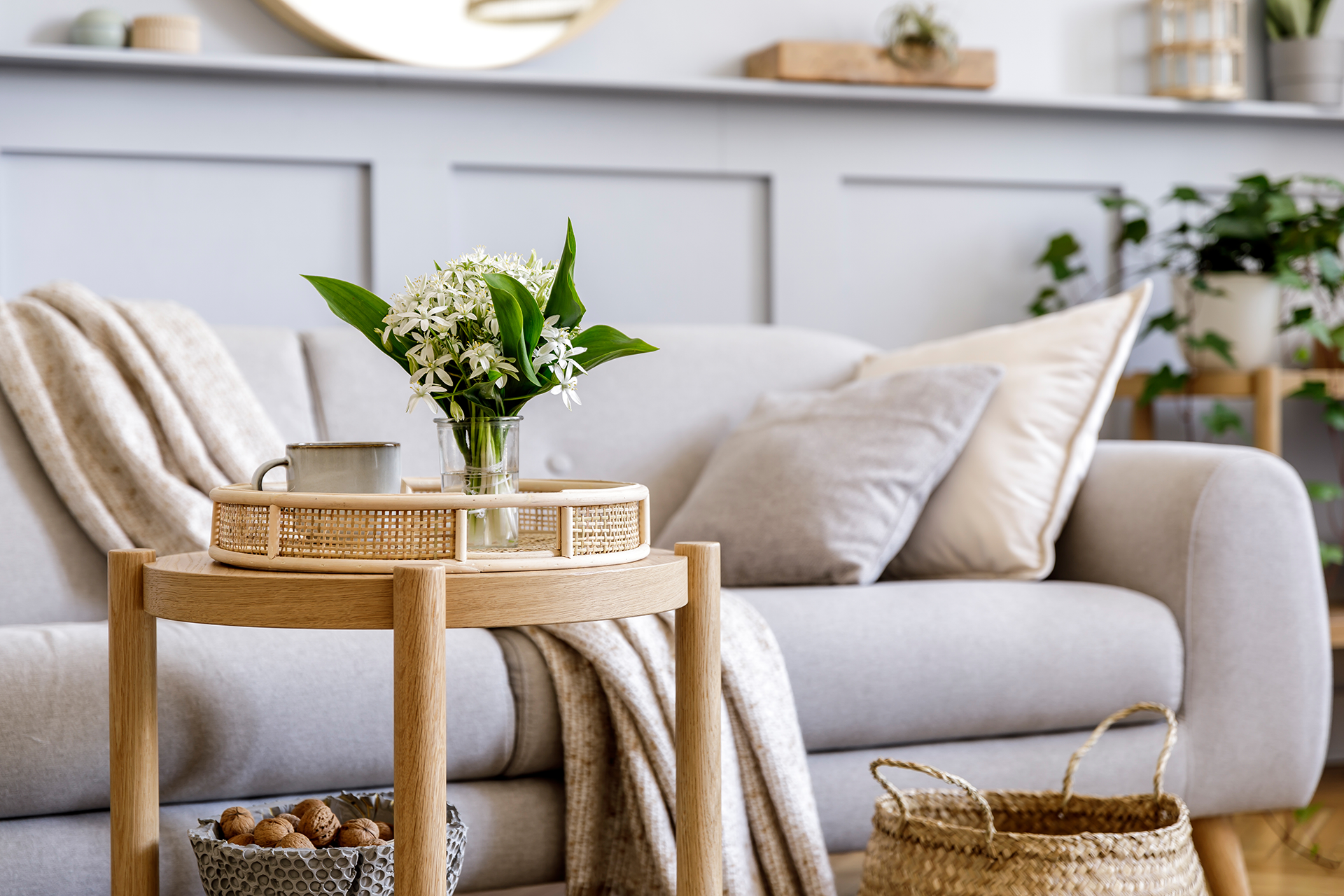 A living room with a couch and a table with a vase of flowers on it.