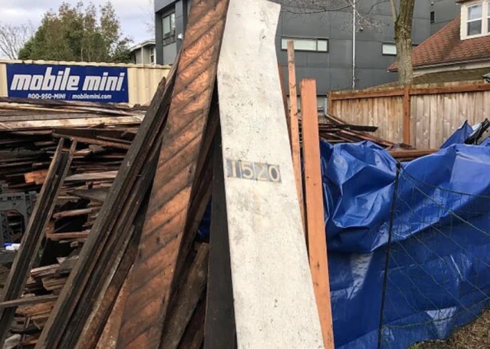 A pile of wood is sitting in front of a mobile mini sign