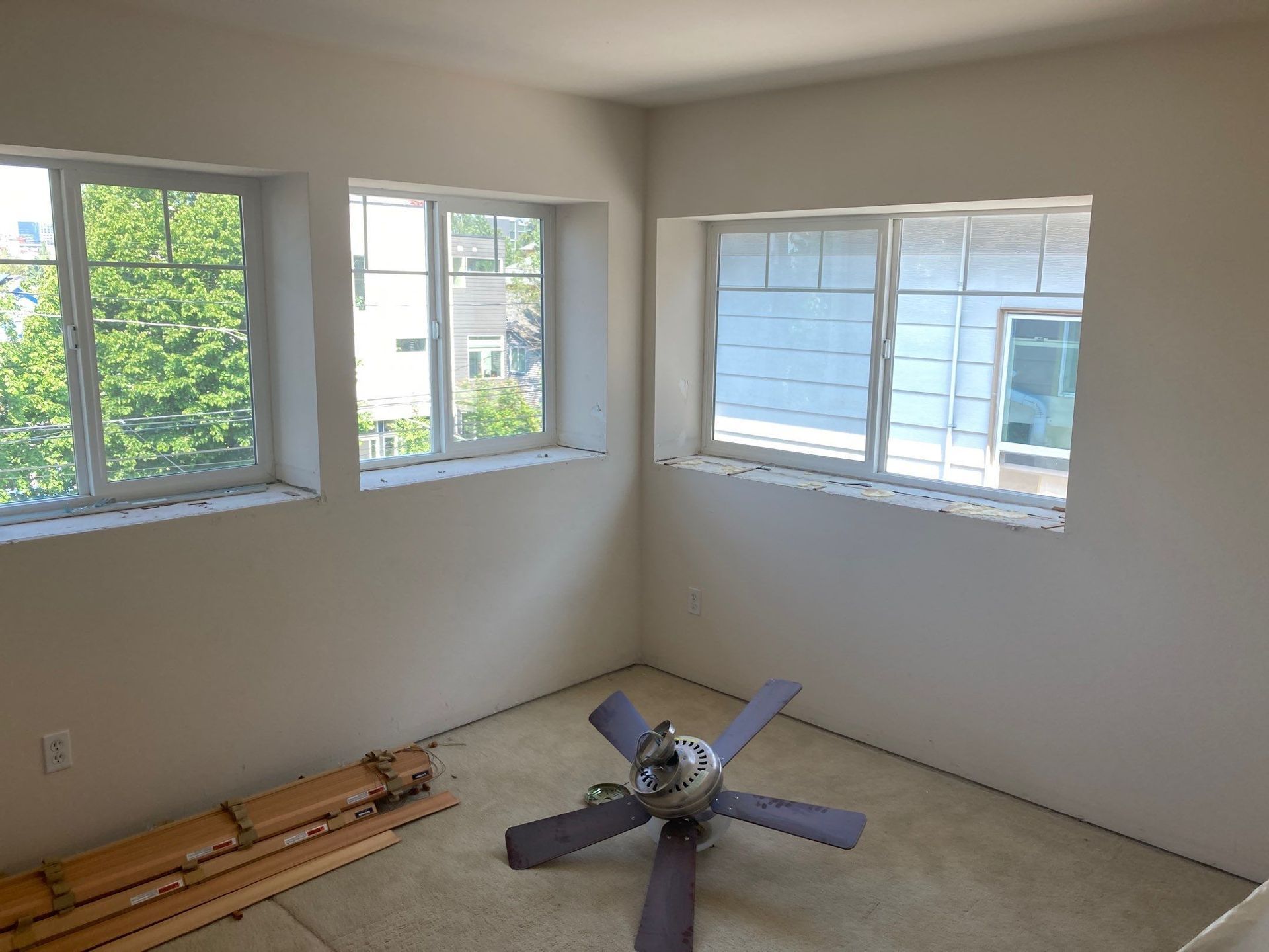 A room with a ceiling fan and a lot of windows