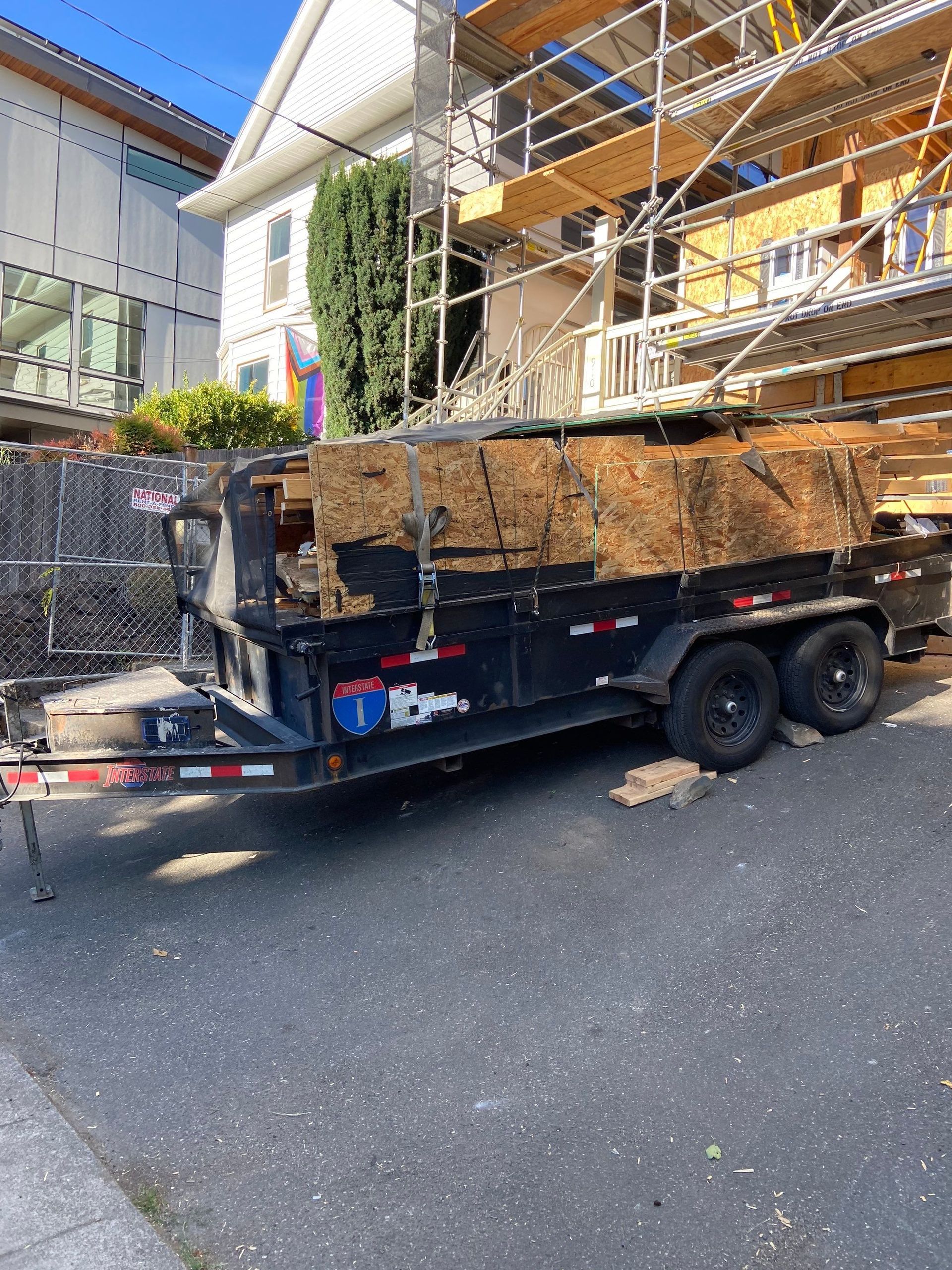 A dump truck is parked on the side of the road in front of a building under construction.