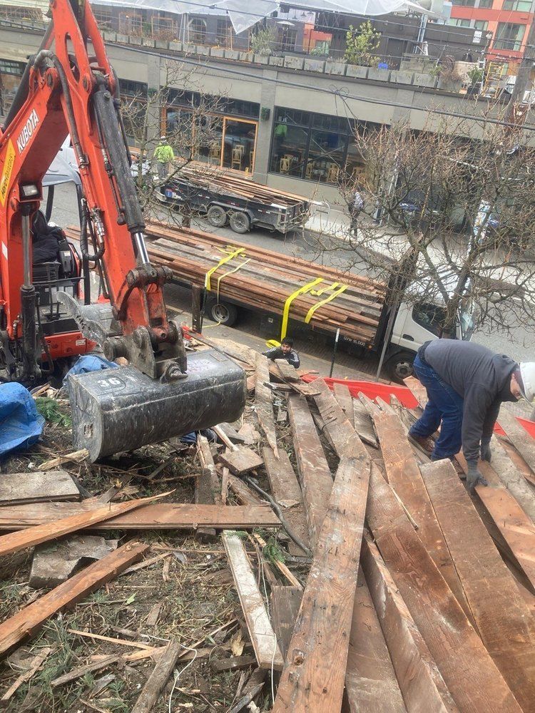 A man is working on a pile of wood next to a truck.
