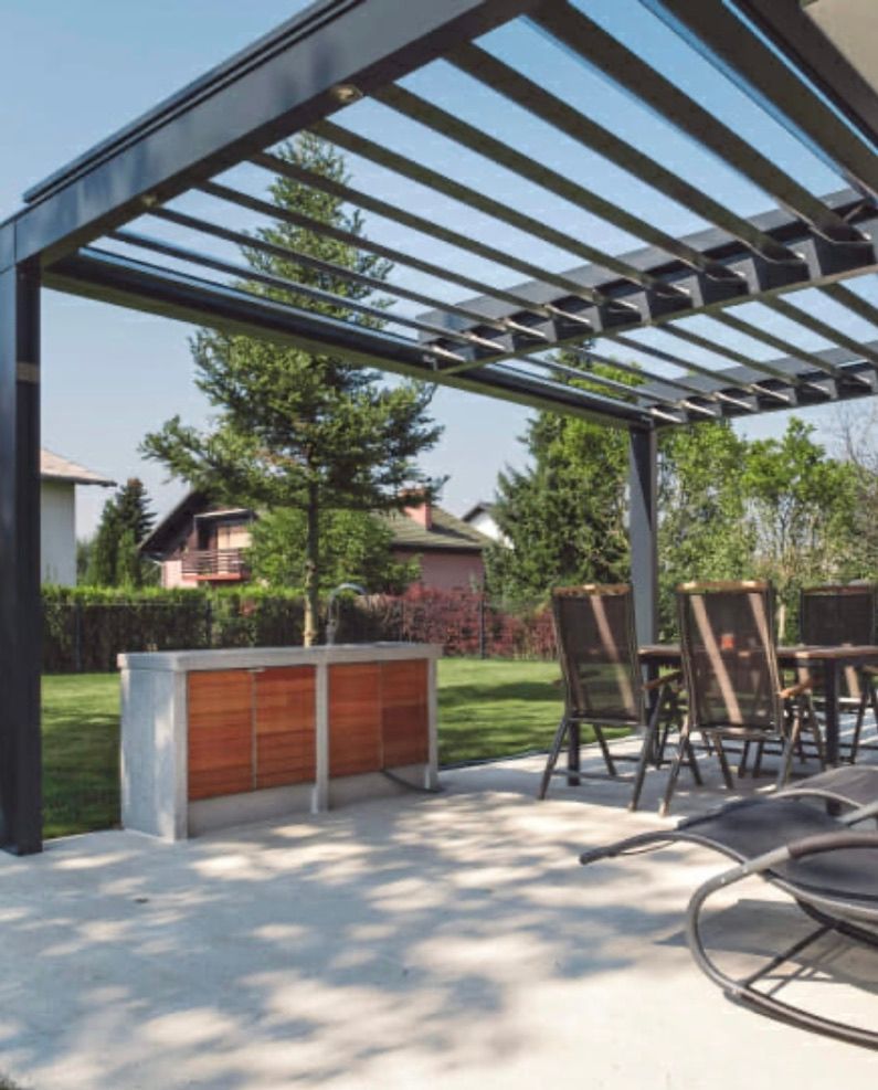 Un patio avec une table et des chaises sous une pergola