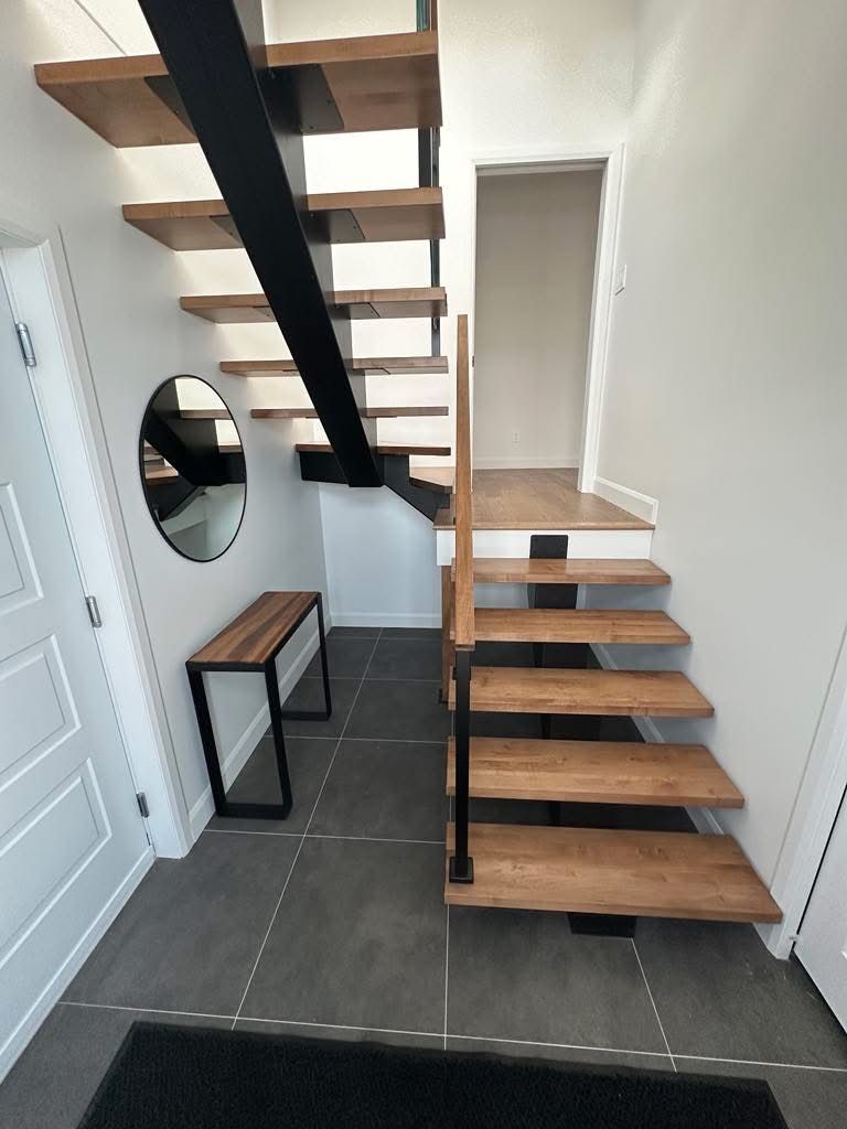 Un couloir avec des escaliers en bois et un miroir