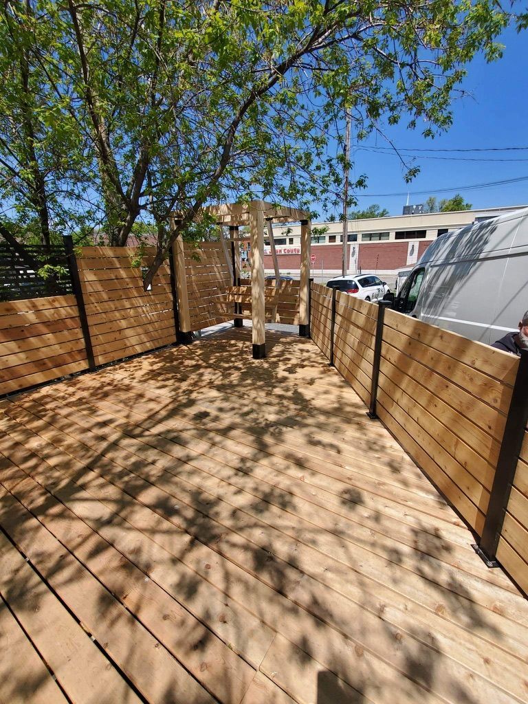 Une terrasse en bois avec une clôture et des arbres en arrière-plan.