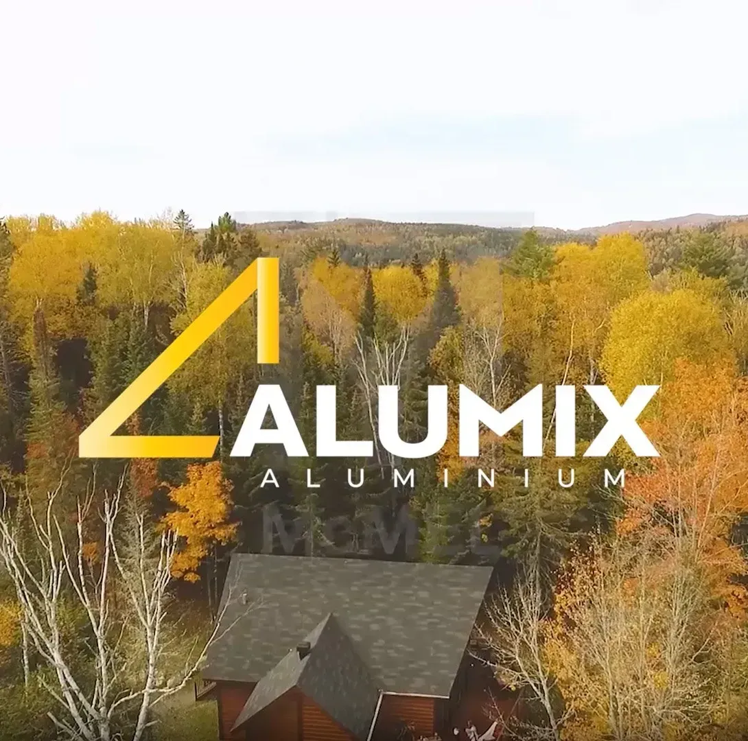 Une vue aérienne d'une maison dans les bois avec le logo d'Alumix