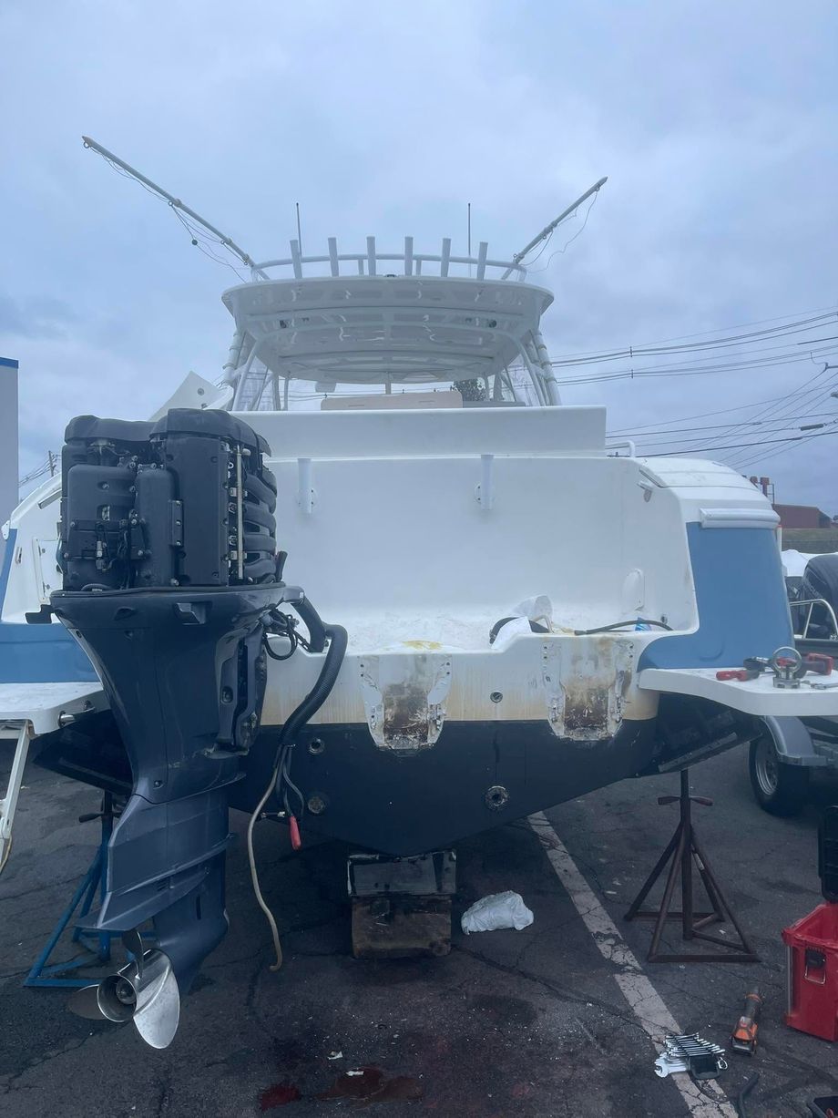 White boat stern with outboard motor and fishing rods on a wet dock under a cloudy sky