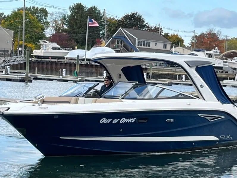 Blue and white motorboat docked at a marina with houses and an American flag in the background