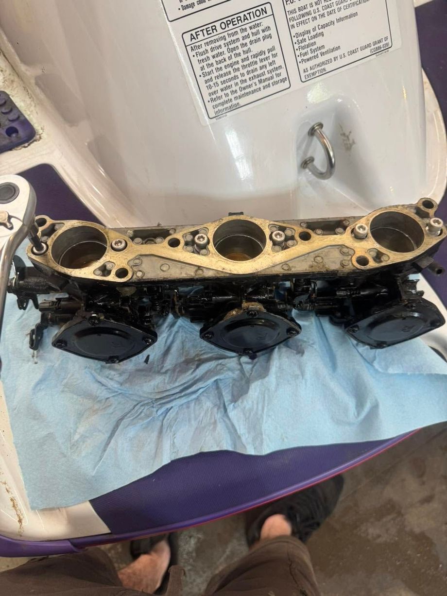 Engine head gasket laid on blue paper towels inside a white sink or wash basin.