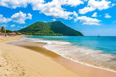 A beach with a mountain in the background and a boat in the ocean.