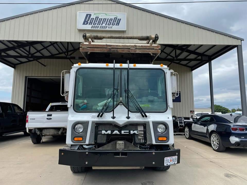 A white Mack truck parked in front of a metal commercial building with a 