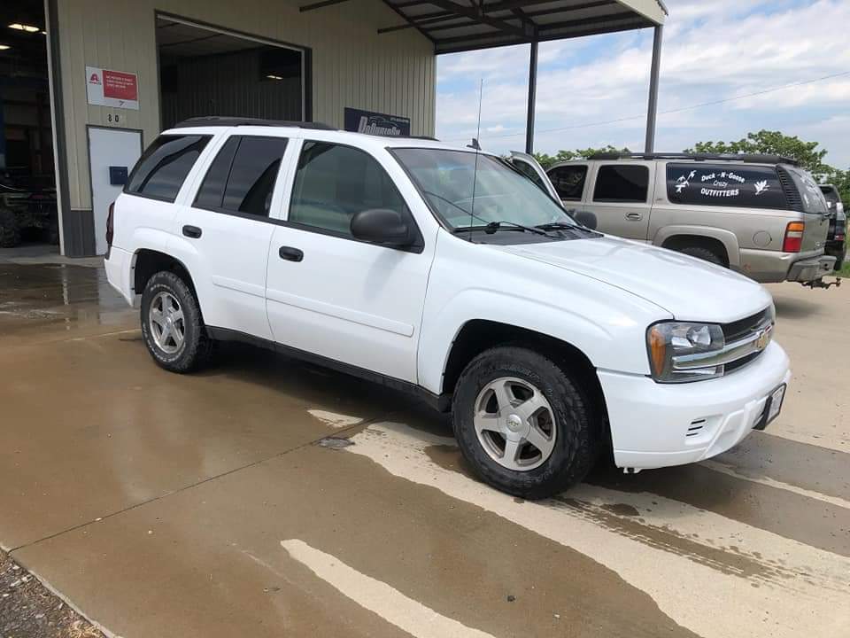 A white Chevrolet Trailblazer SUV parked on a concrete surface in front of a garage building.
