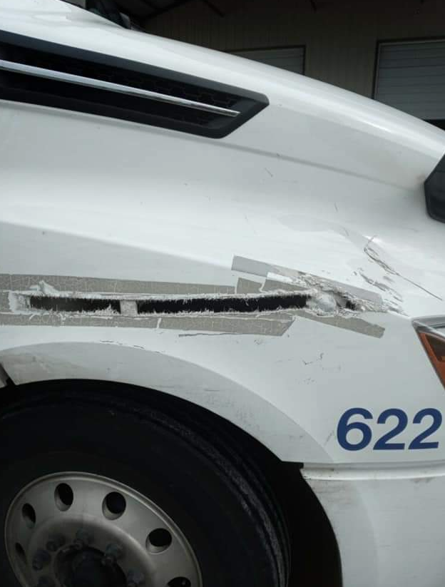 Close-up of a damaged, white truck fender featuring a torn plastic vent and the blue number 622 on the side panel.
