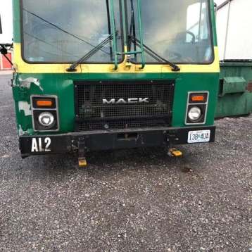 Front view of a green and yellow Mack truck parked on gravel with the label 