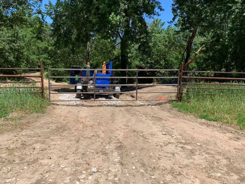 a blue truck is parked in front of a metal gate a blue truck is parked in front of a metal gate