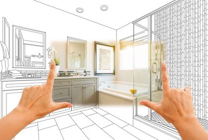 Hands framing a partially sketched bathroom design with a vanity, tub, and shower.
