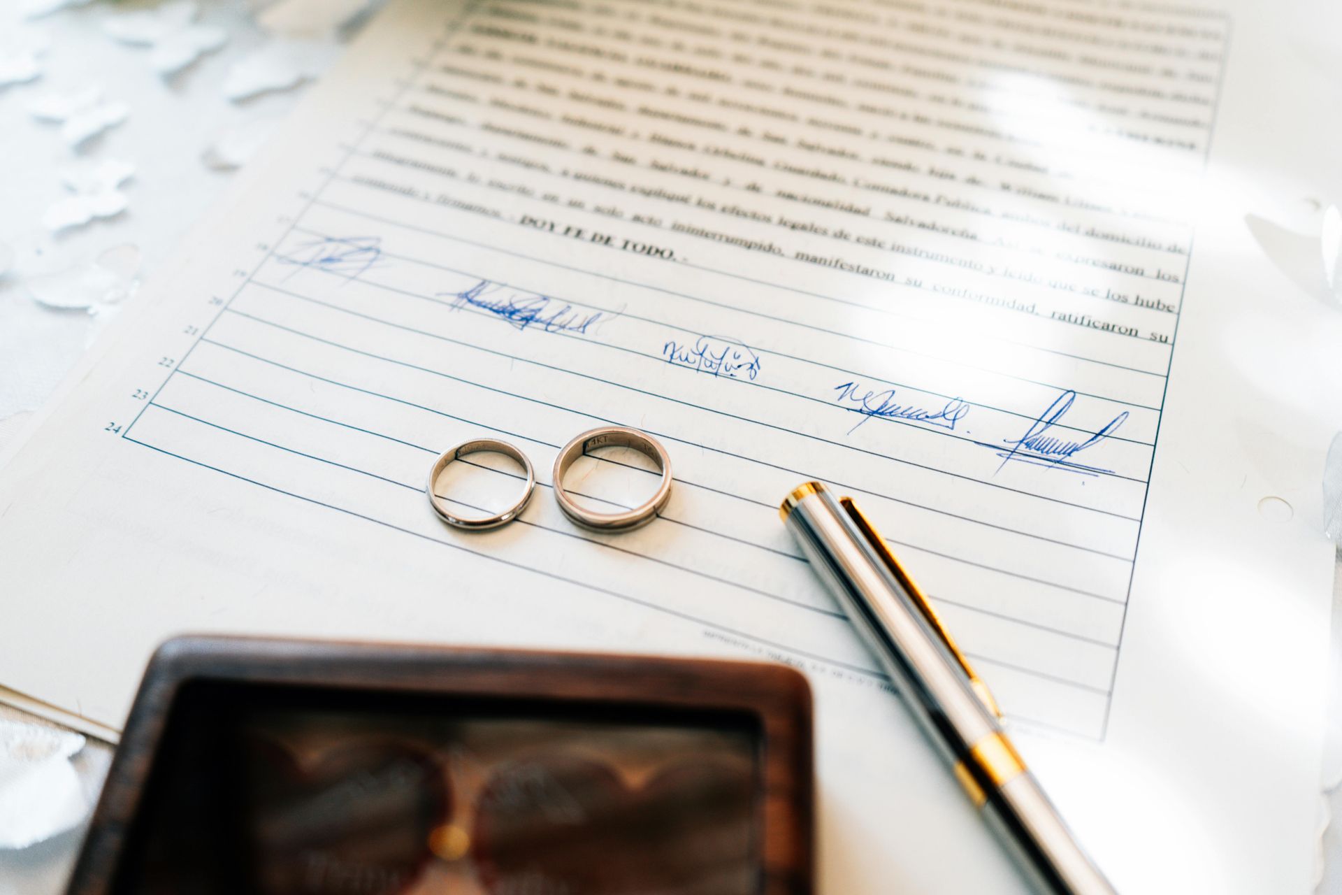 two rings and a pen sitting on a marriage certificate