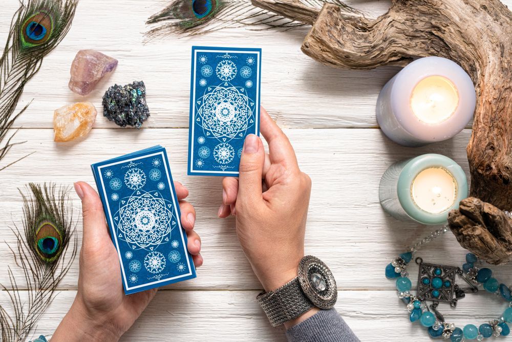 A person is holding two tarot cards in their hands.