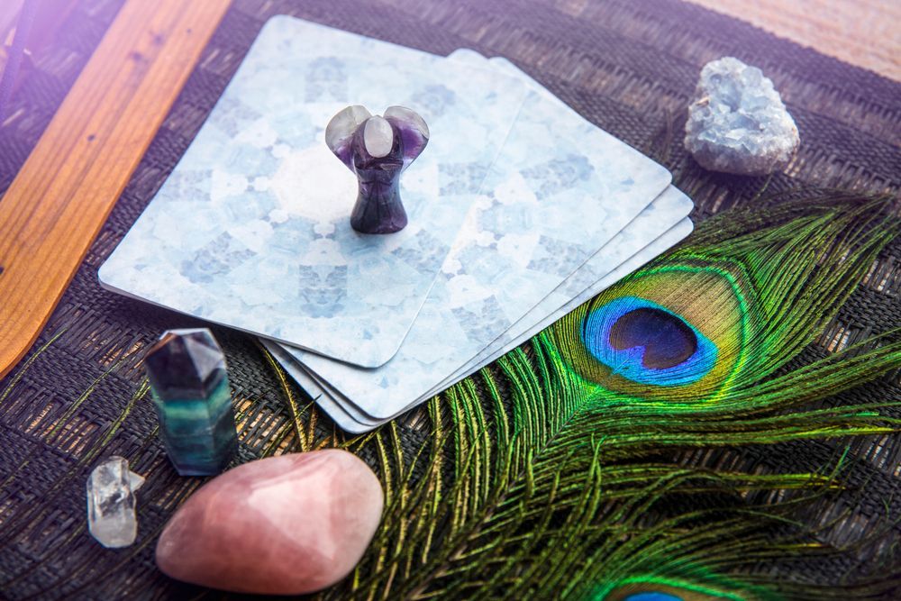 A stack of tarot cards sitting on top of a peacock feather.