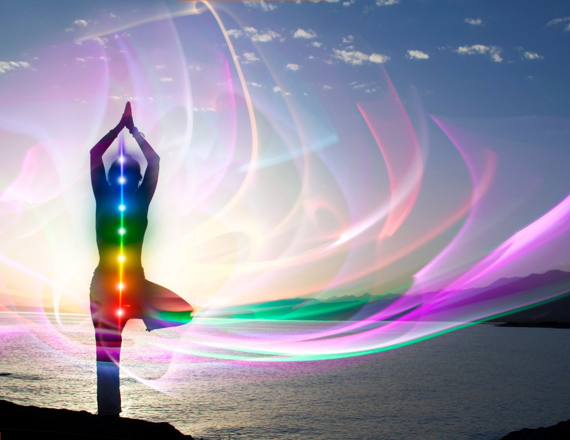 A silhouette of a woman in a yoga pose with rainbow lights behind her