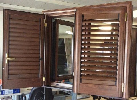 Finestra in legno marrone con persiane aperte e telaio.